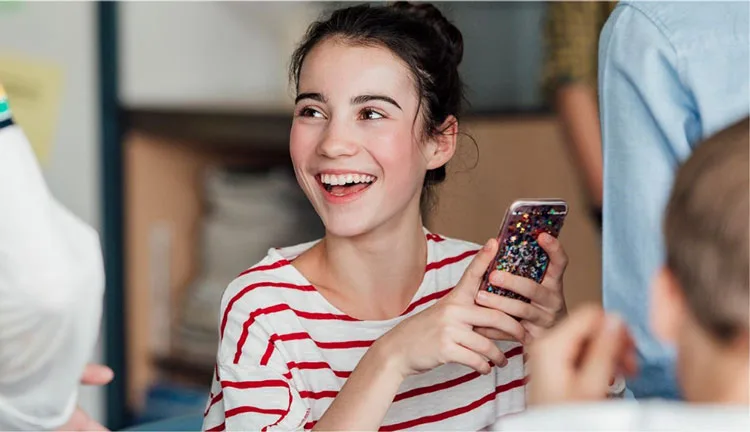 Woman smiling confidently at school looking up from her phone