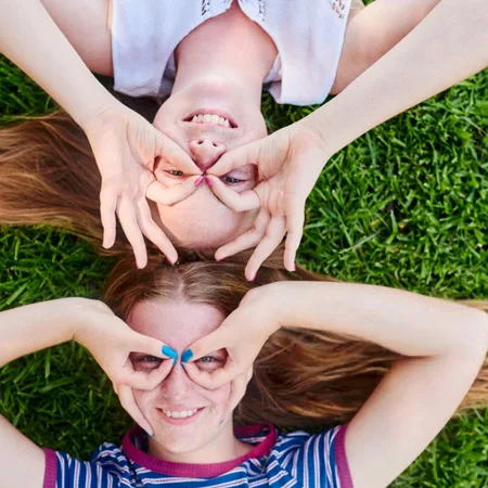 Two girls smiling laying in the grass