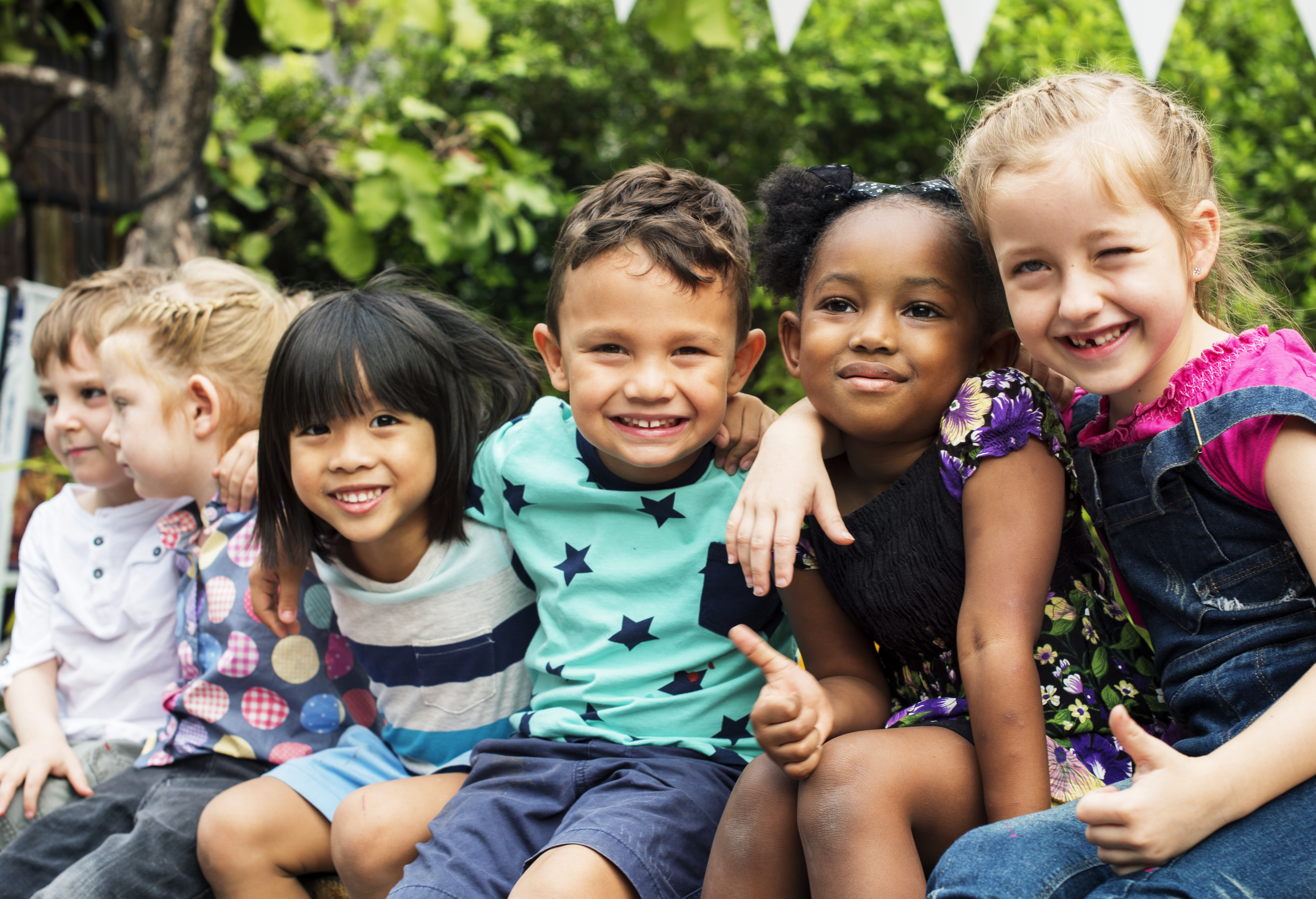 Group of kindergarten kids friends arm around sitting and smiling